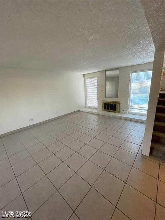 5243 Sunnywood Dr, Las Vegas, NV 89120 - unfurnished living room featuring healthy amount of natural light, stairway, light tile patterned floors, a glass covered fireplace, and a textured ceiling