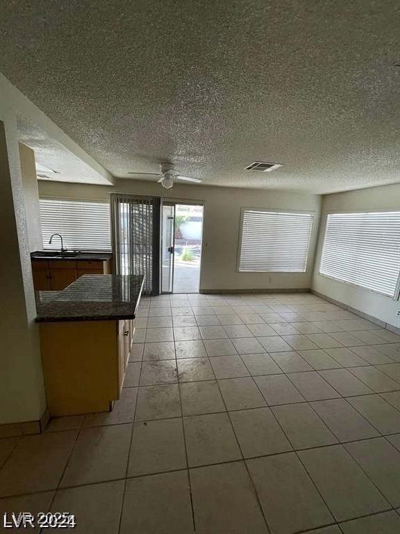 5243 Sunnywood Dr, Las Vegas, NV 89120 - unfurnished living room with a textured ceiling, a sink, light tile patterned flooring, ceiling fan, and baseboards