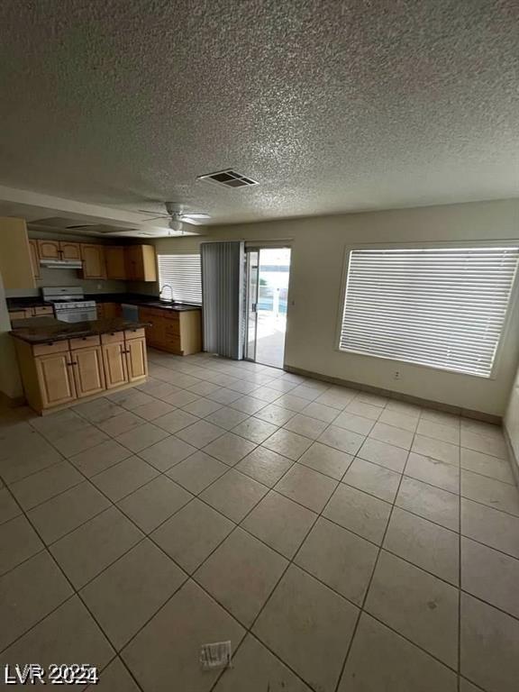5243 Sunnywood Dr, Las Vegas, NV 89120 - kitchen with dark countertops, white gas range, a textured ceiling, a ceiling fan, and light tile patterned floors