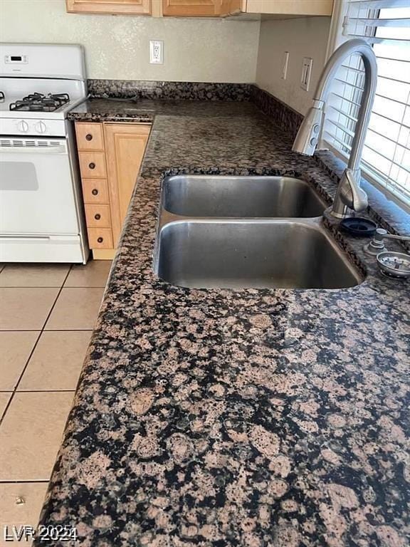 5243 Sunnywood Dr, Las Vegas, NV 89120 - kitchen with white gas range oven, a sink, dark countertops, light tile patterned flooring, and light brown cabinetry
