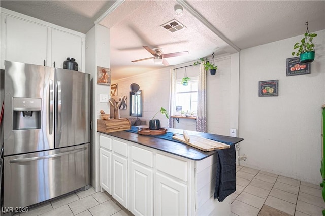 108 Verdy Ln, Las Vegas, NV 89101 - kitchen featuring stainless steel fridge, light tile patterned floors, a ceiling fan, a textured ceiling, and white cabinetry