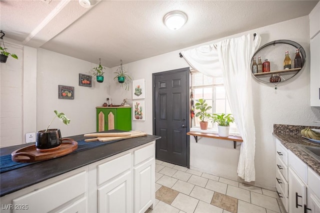 108 Verdy Ln, Las Vegas, NV 89101 - kitchen with dark countertops, white cabinetry, a textured ceiling, light tile patterned floors, and open shelves