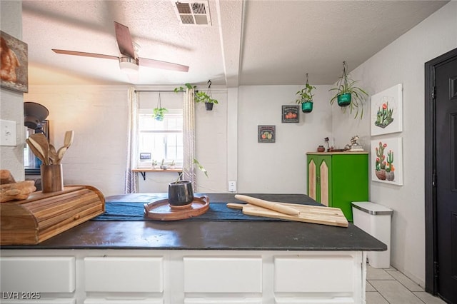 108 Verdy Ln, Las Vegas, NV 89101 - kitchen featuring white cabinetry, ceiling fan, a textured ceiling, light tile patterned floors, and dark countertops