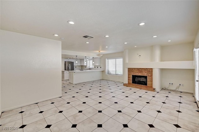 2917 Broken Willow Cir, Las Vegas, NV 89117 - unfurnished living room featuring a fireplace with raised hearth, recessed lighting, a sink, and light floors