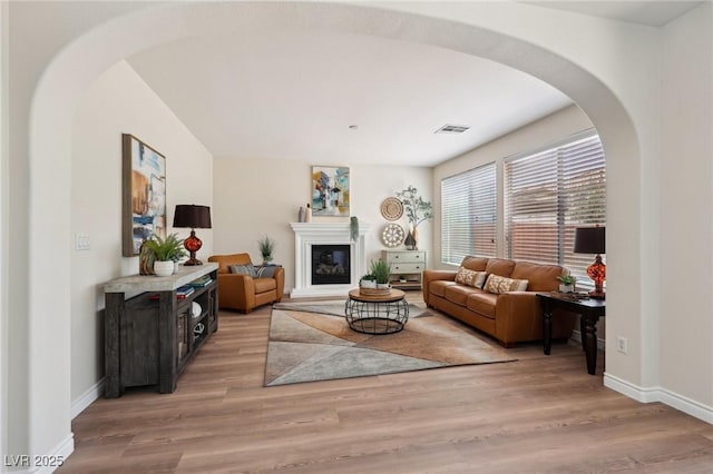 11707 Longworth Rd, Las Vegas, NV 89135 - living room featuring arched walkways, light wood-type flooring, baseboards, and a glass covered fireplace