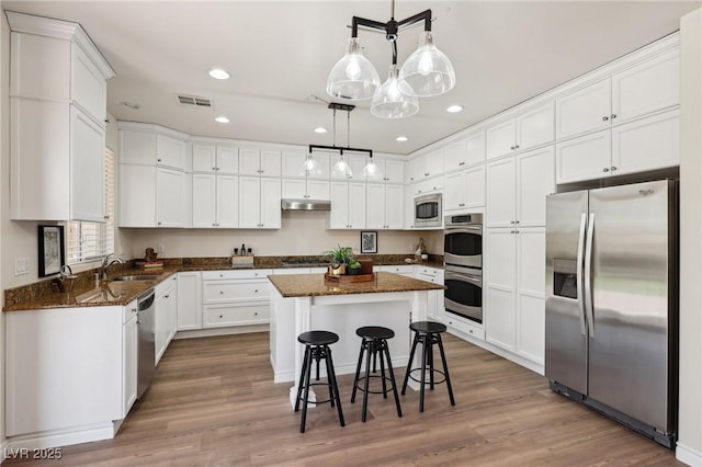11707 Longworth Rd, Las Vegas, NV 89135 - kitchen featuring stainless steel appliances, under cabinet range hood, a kitchen island, white cabinetry, and recessed lighting