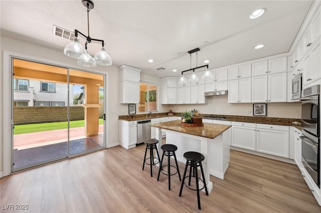 11707 Longworth Rd, Las Vegas, NV 89135 - kitchen with stainless steel appliances, under cabinet range hood, light wood-type flooring, white cabinetry, and recessed lighting