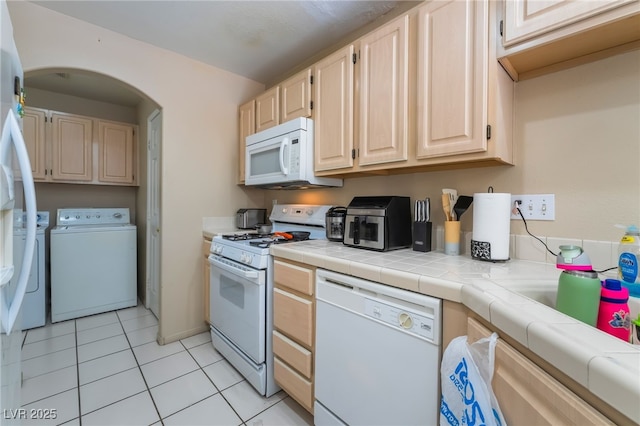 3950 S Sandhill Rd Unit 130, Las Vegas, NV 89121 - kitchen with white appliances, independent washer and dryer, light tile patterned floors, light brown cabinets, and tile countertops