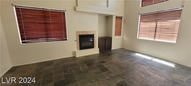 4821 Whisper Lake Ave, Las Vegas, NV 89131 - unfurnished living room with a tiled fireplace, dark stone finish flooring, and baseboards