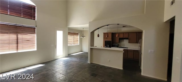 4821 Whisper Lake Ave, Las Vegas, NV 89131 - kitchen with a towering ceiling, arched walkways, light countertops, freestanding refrigerator, and dark stone finish flooring