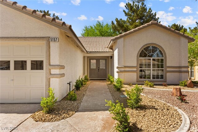 5157 Future Dr, Las Vegas, NV 89130 - view of exterior entry featuring stucco siding, an attached garage, and a tiled roof