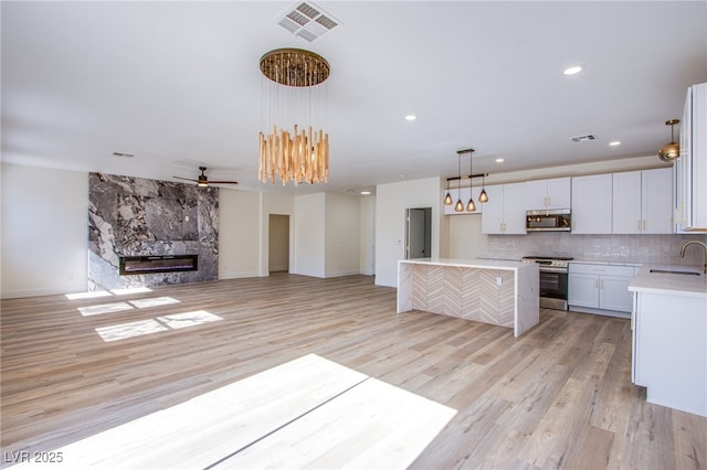 5653 Artesia Lake Ct, Las Vegas, NV 89118 - unfurnished living room featuring a sink, light wood-style flooring, baseboards, a high end fireplace, and recessed lighting