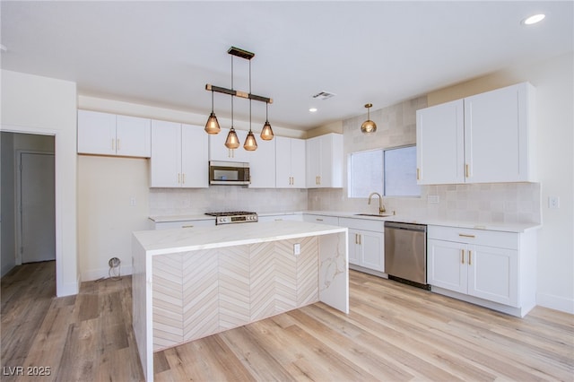 5653 Artesia Lake Ct, Las Vegas, NV 89118 - kitchen with appliances with stainless steel finishes, a sink, white cabinetry, a center island, and tasteful backsplash