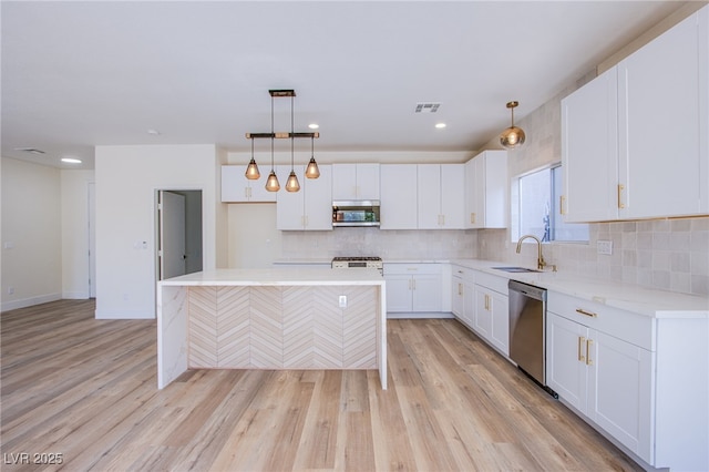 5653 Artesia Lake Ct, Las Vegas, NV 89118 - kitchen with appliances with stainless steel finishes, a sink, light wood-style flooring, backsplash, and white cabinets