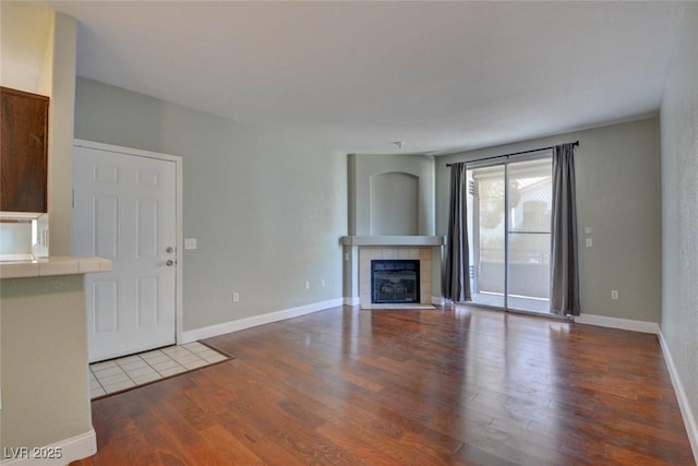 1405 S Nellis Blvd Unit 2117, Las Vegas, NV 89104 - unfurnished living room with wood finished floors, a tiled fireplace, and baseboards