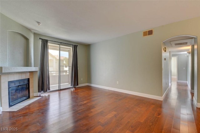 1405 S Nellis Blvd Unit 2117, Las Vegas, NV 89104 - unfurnished living room featuring wood finished floors, a fireplace, baseboards, and arched walkways