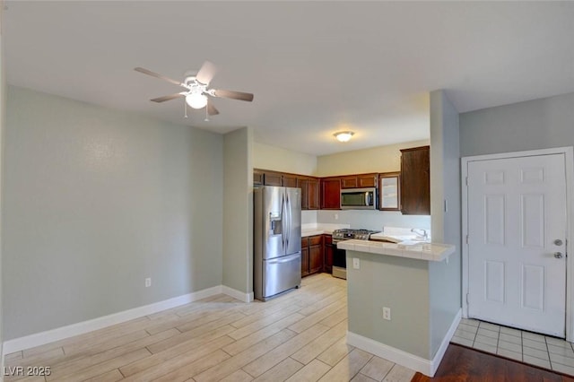 1405 S Nellis Blvd Unit 2117, Las Vegas, NV 89104 - kitchen featuring appliances with stainless steel finishes, tile counters, a peninsula, light wood finished floors, and a ceiling fan