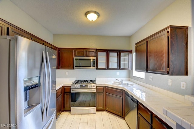 1405 S Nellis Blvd Unit 2117, Las Vegas, NV 89104 - kitchen with appliances with stainless steel finishes, a sink, tile counters, and glass insert cabinets