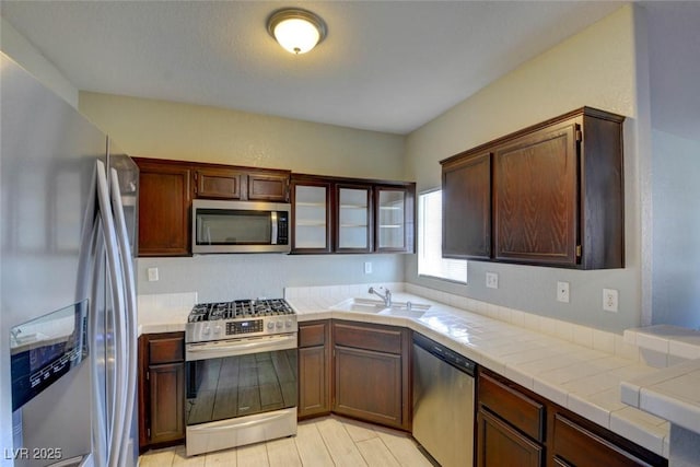 1405 S Nellis Blvd Unit 2117, Las Vegas, NV 89104 - kitchen with appliances with stainless steel finishes, a sink, tile countertops, glass insert cabinets, and light wood finished floors