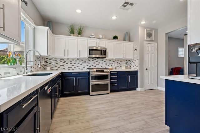 2425 Sturrock Dr, Henderson, NV 89044 - kitchen featuring appliances with stainless steel finishes, a sink, white cabinetry, blue cabinetry, and light countertops