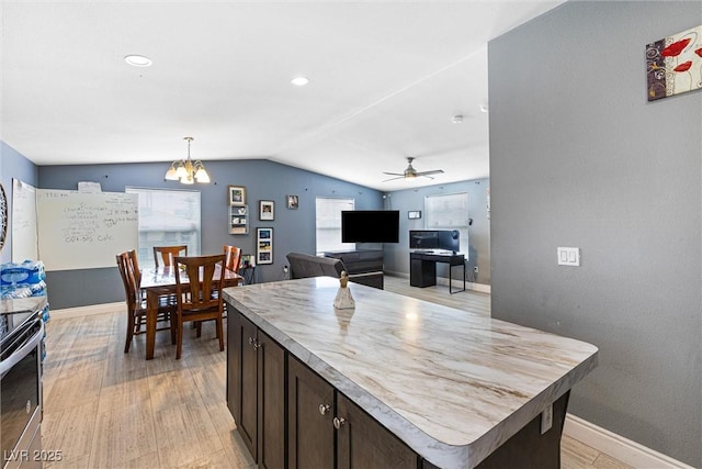 320 W Van Buren Ave, Las Vegas, NV 89106 - kitchen with vaulted ceiling, dark brown cabinetry, a chandelier, light wood finished floors, and stainless steel range with electric stovetop
