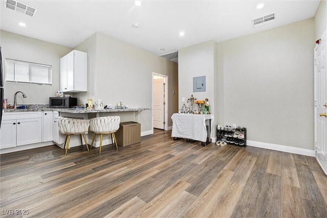 320 W Van Buren Ave, Las Vegas, NV 89106 - kitchen with stainless steel microwave, light stone counters, a sink, wood finished floors, and white cabinetry