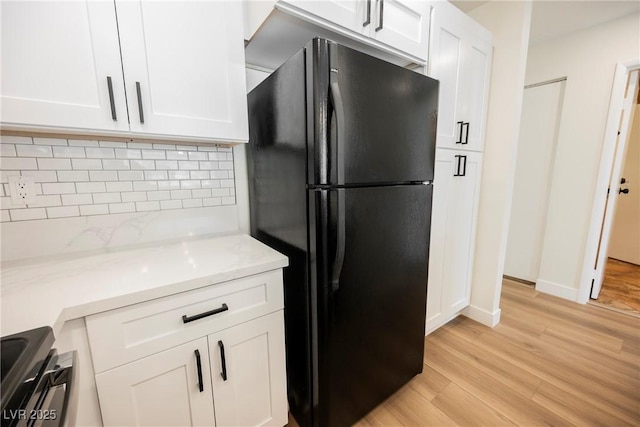 5516 Orchard Ln Unit 0, Las Vegas, NV 89110 - kitchen with freestanding refrigerator, light wood-type flooring, decorative backsplash, stainless steel electric stove, and white cabinets