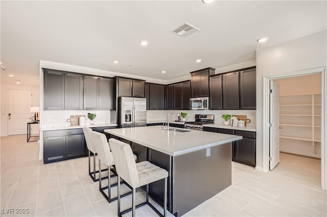 9588 Archer Peak Ct, Las Vegas, NV 89143 - kitchen with appliances with stainless steel finishes, a sink, a kitchen island with sink, light countertops, and a breakfast bar area