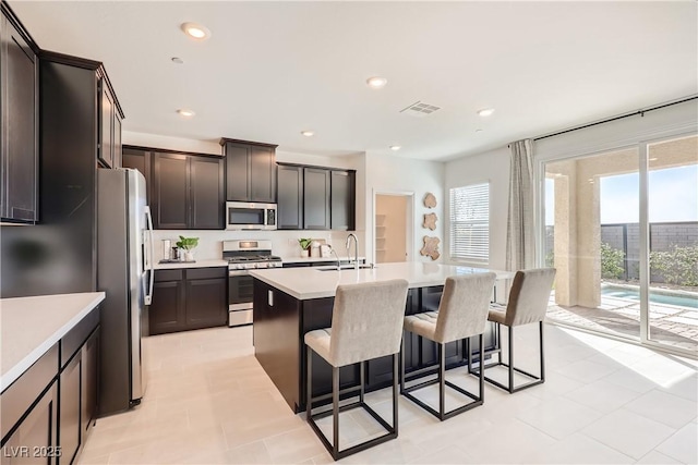 9588 Archer Peak Ct, Las Vegas, NV 89143 - kitchen featuring appliances with stainless steel finishes, a sink, a breakfast bar, light countertops, and a center island with sink