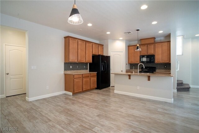 7715 Peaceful Trellis Dr, Las Vegas, NV 89179 - kitchen with black appliances, brown cabinets, baseboards, tasteful backsplash, and light wood finished floors
