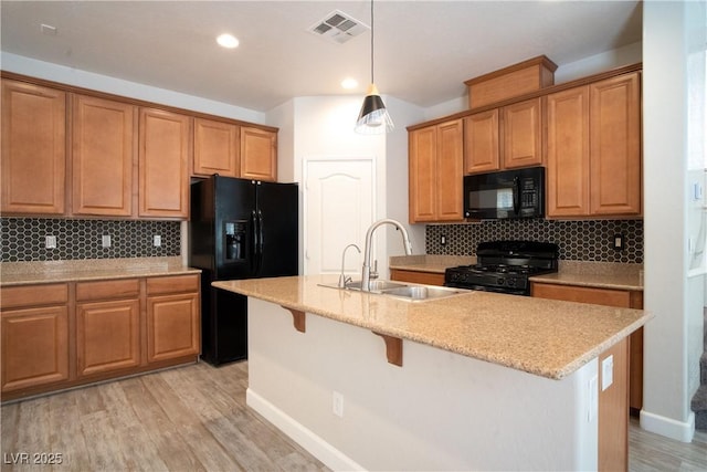 7715 Peaceful Trellis Dr, Las Vegas, NV 89179 - kitchen with black appliances, a sink, decorative backsplash, light wood finished floors, and hanging light fixtures