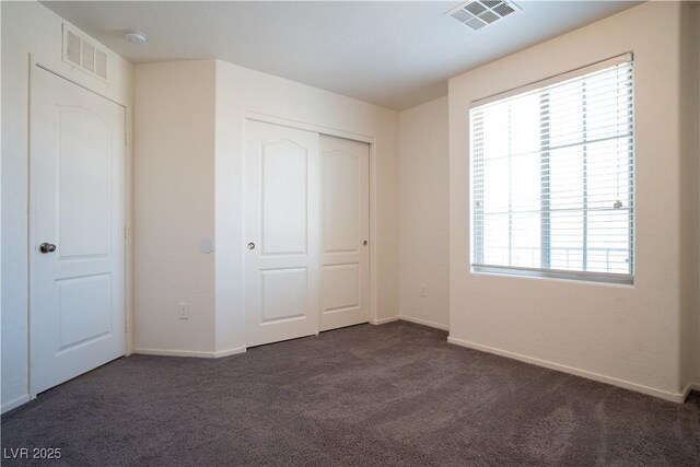 7715 Peaceful Trellis Dr, Las Vegas, NV 89179 - unfurnished bedroom with dark colored carpet, multiple windows, baseboards, and a closet