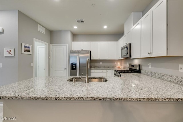 2870 Turnstone Ridge St, Henderson, NV 89044 - kitchen featuring appliances with stainless steel finishes, light stone countertops, a peninsula, white cabinetry, and recessed lighting