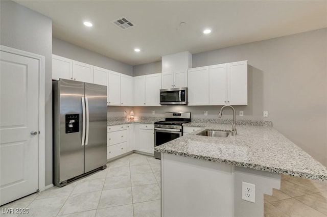 2870 Turnstone Ridge St, Henderson, NV 89044 - kitchen with stainless steel appliances, a sink, a peninsula, light stone countertops, and white cabinets