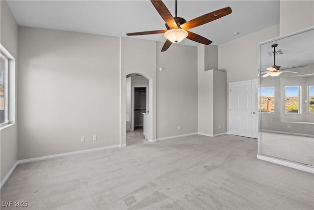 2158 Shubert Ave, Henderson, NV 89052 - unfurnished living room with a ceiling fan, arched walkways, light colored carpet, a towering ceiling, and baseboards
