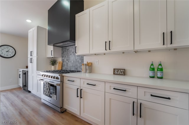 9705 Standard Ave, Las Vegas, NV 89129 - kitchen featuring high end stove, wall chimney range hood, tasteful backsplash, white cabinets, and light countertops