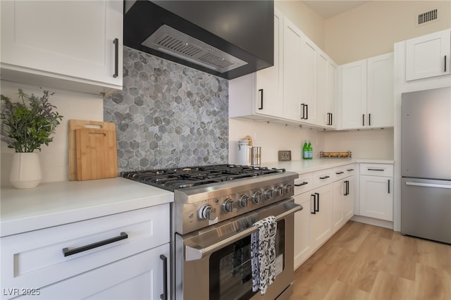 9705 Standard Ave, Las Vegas, NV 89129 - kitchen featuring appliances with stainless steel finishes, custom range hood, light countertops, tasteful backsplash, and light wood-type flooring