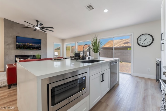 9705 Standard Ave, Las Vegas, NV 89129 - kitchen with a sink, stainless steel appliances, white cabinets, an island with sink, and light wood finished floors