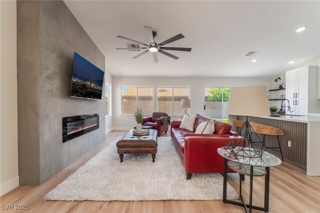 9705 Standard Ave, Las Vegas, NV 89129 - living room featuring light wood finished floors, ceiling fan, a glass covered fireplace, baseboards, and recessed lighting