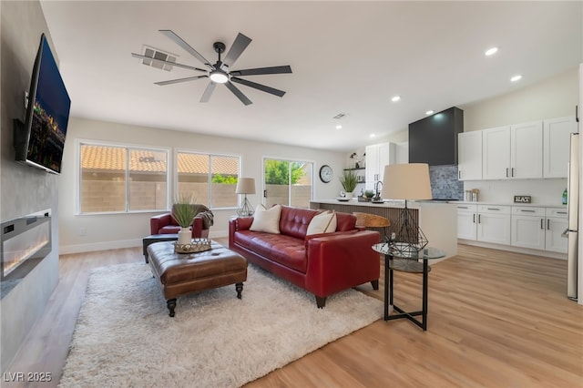 9705 Standard Ave, Las Vegas, NV 89129 - living room with ceiling fan, light wood finished floors, a large fireplace, recessed lighting, and baseboards
