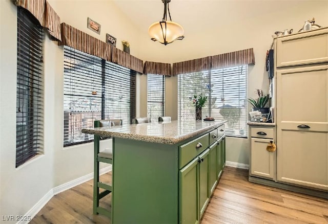 3473 Conough Ln, Las Vegas, NV 89129 - kitchen featuring green cabinetry, baseboards, light wood-style floors, a kitchen bar, and a peninsula