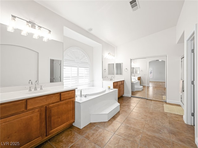 5120 Mirage Garden St, Las Vegas, NV 89130 - bathroom featuring two vanities, a garden tub, plenty of natural light, high vaulted ceiling, and tile patterned floors