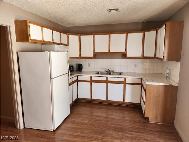 377 N 16th St, Las Vegas, NV 89101 - kitchen with freestanding refrigerator, a sink, tasteful backsplash, dark wood-type flooring, and tile countertops