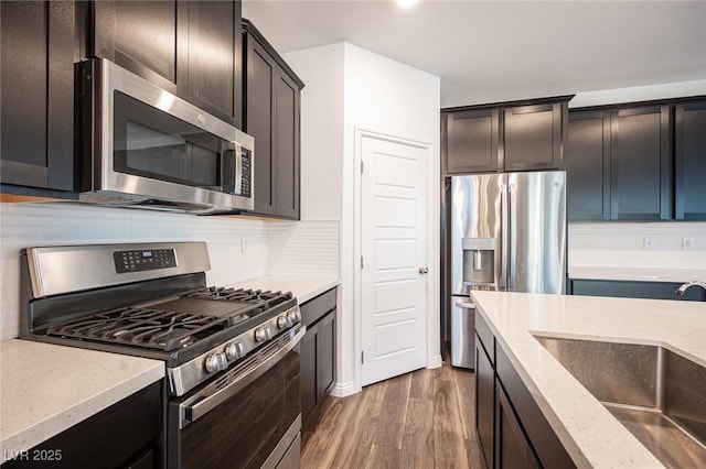 871 Aurelie Ridge St, Henderson, NV 89011 - kitchen featuring appliances with stainless steel finishes, a sink, dark wood finished floors, light stone counters, and decorative backsplash