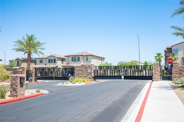 871 Aurelie Ridge St, Henderson, NV 89011 - view of asphalt road featuring a gate, sidewalks, traffic signs, a gated entry, and a residential view