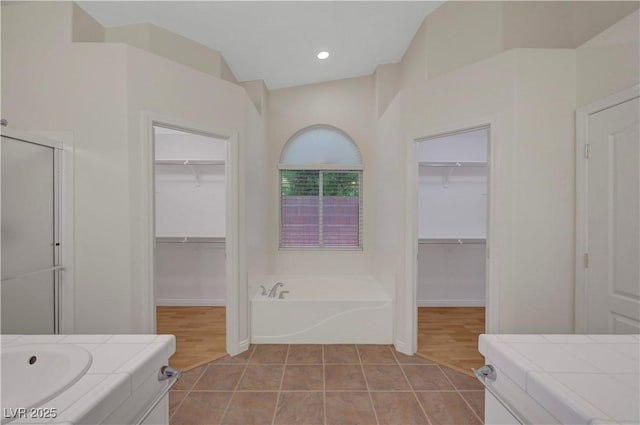 4197 Bottiglia Ave, Las Vegas, NV 89141 - bathroom featuring a spacious closet, a garden tub, a stall shower, and vanity