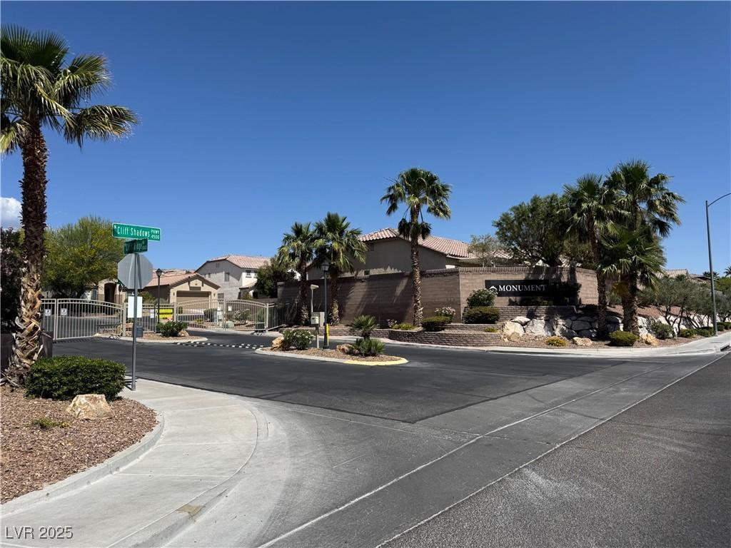 10645 Alpine Frost Ct, Las Vegas, NV 89129 - view of asphalt road featuring traffic signs, curbs, a residential view, sidewalks, and a gate