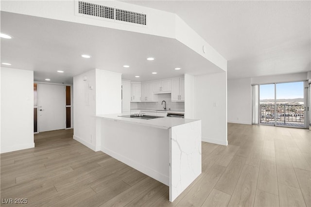3111 Bel Air Dr Unit 24G, Las Vegas, NV 89109 - kitchen with light countertops, a sink, light wood-style floors, a peninsula, and recessed lighting