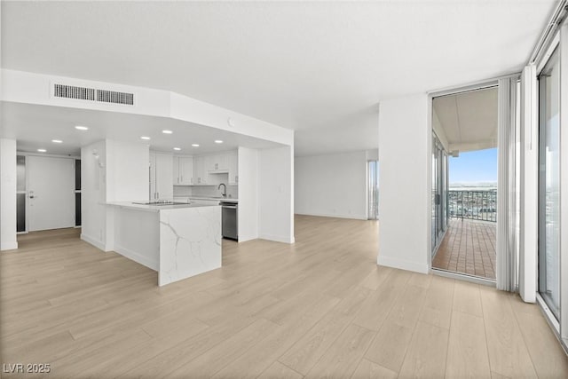 3111 Bel Air Dr Unit 24G, Las Vegas, NV 89109 - kitchen featuring open floor plan, light wood-type flooring, stainless steel dishwasher, white cabinetry, and a peninsula