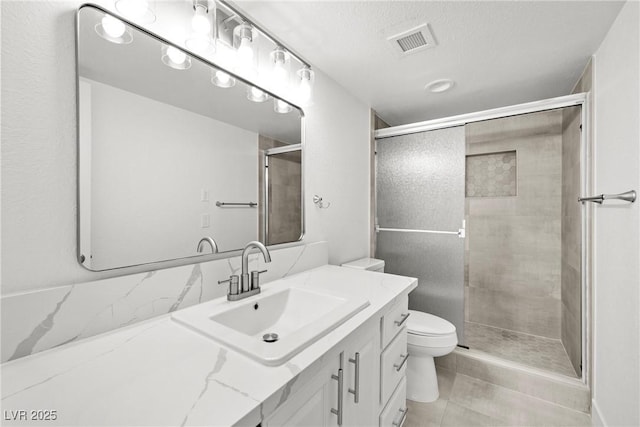 3111 Bel Air Dr Unit 24G, Las Vegas, NV 89109 - bathroom featuring toilet, vanity, a shower stall, a textured ceiling, and tile patterned flooring
